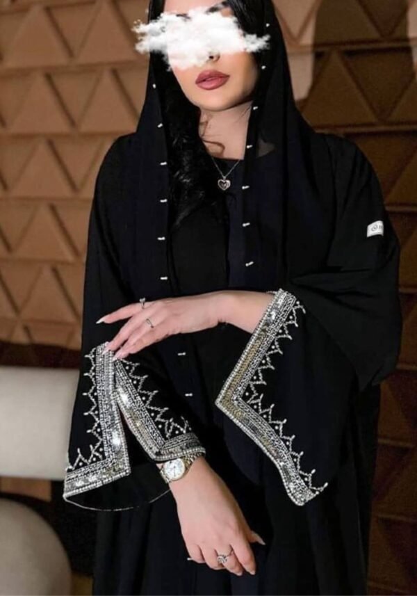 A closer front view of the Klassische Krepp-Abaya Zeitlos, showcasing intricate silver and goldish patterns around the hands, elegantly complemented by a watch.