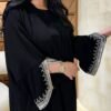 A lady wearing the Klassische Krepp-Abaya Zeitlos, a black abaya adorned with silver and goldish patterns around the hands, elegantly paired with a watch, highlighting timeless sophistication.