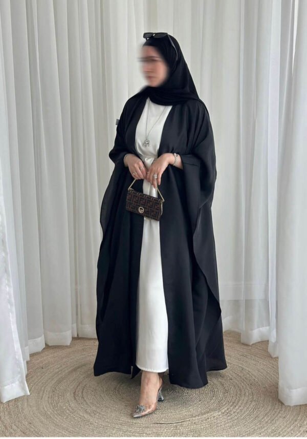 A lady wearing the Lexus Krepp-Ensemble Elegance Plus abaya, featuring a white interior with a black exterior, accessorized with jewelry and a Fendi bag, exuding refined elegance.