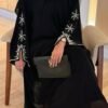 A lady wearing the Royal Chiffon-Abaya Leichtigkeit, a black abaya paired with elegant jewelry, holding a Yves Saint Laurent bag, showcasing luxury and sophistication.