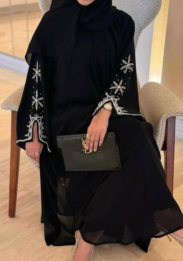 A lady wearing the Royal Chiffon-Abaya Leichtigkeit, a black abaya paired with elegant jewelry, holding a Yves Saint Laurent bag, showcasing luxury and sophistication.