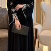A lady wearing the Royal Chiffon-Abaya Leichtigkeit, a black abaya paired with elegant jewelry, holding a Yves Saint Laurent bag, showcasing luxury and sophistication.
