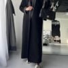A lady wearing the Klassische Krepp-Abaya Eleganz, elegantly holding a black bag, showcasing timeless sophistication.