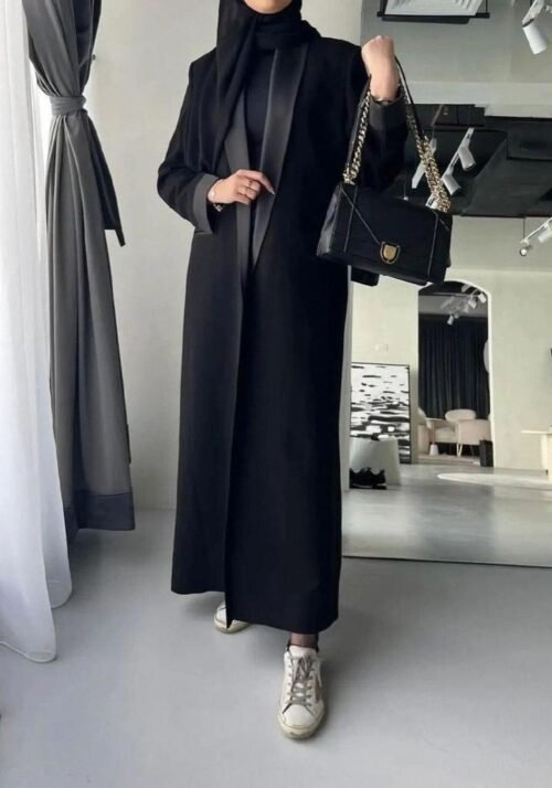A lady wearing the Klassische Krepp-Abaya Eleganz, elegantly holding a black bag, showcasing timeless sophistication.