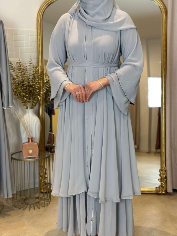 Eine Frau trägt die königliche Chiffon-Abaya in Himmelblau mit glitzernden Akzenten, ideal für elegante Anlässe.