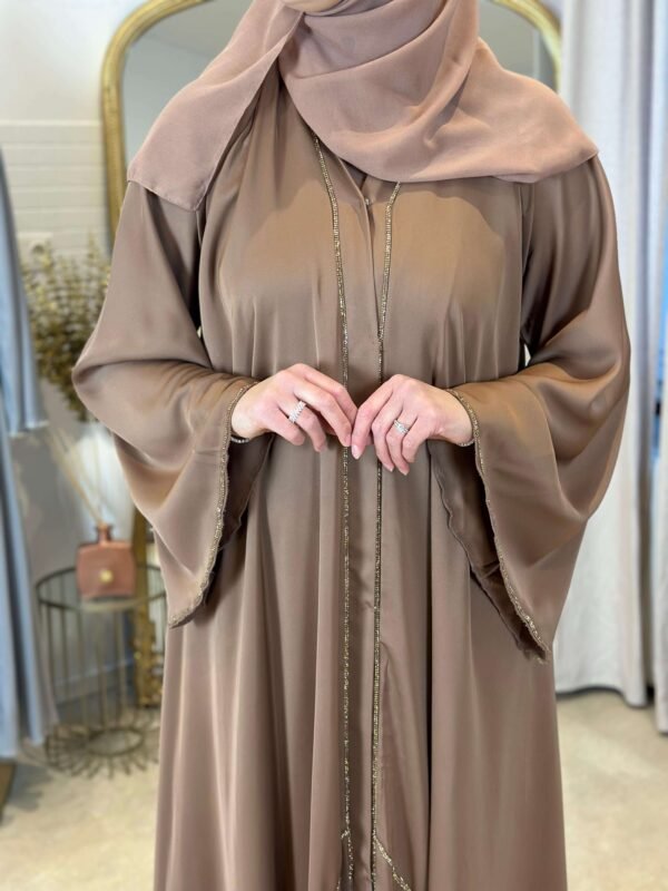 Nahaufnahme der luxuriösen Goldakzente an den Ärmeln und entlang der Vorderseite der braunen Internet Krepp-Abaya.