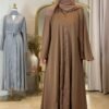 Eine elegante braune Abaya aus Internet Kreppstoff mit feinen Goldakzenten, präsentiert in einer modernen Umgebung.