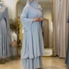 Eine Frau präsentiert die königliche Chiffon-Abaya in Himmelblau von der Seite, mit eleganten Akzenten und fließendem Schnitt.