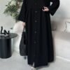 A lady wearing the Krepp-Abaya Essenz, an all-black abaya paired with a black bag and sporty sneakers, combining elegance with a casual touch.