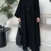 A lady wearing the Krepp-Abaya Essenz, an all-black abaya paired with a black bag and sporty sneakers, combining elegance with a casual touch.