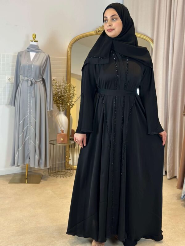 Eine Frau trägt die Luxus Krepp-Internet-Abaya in Schwarz mit dezenten Glitzerakzenten, perfekt für formelle Anlässe.