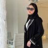 Eine Frau trägt die Royal Krepp-Abaya, ein zweiteiliges Set aus schwarzem Kreppstoff mit edlen Details, aufgenommen in einem modernen Raum.
