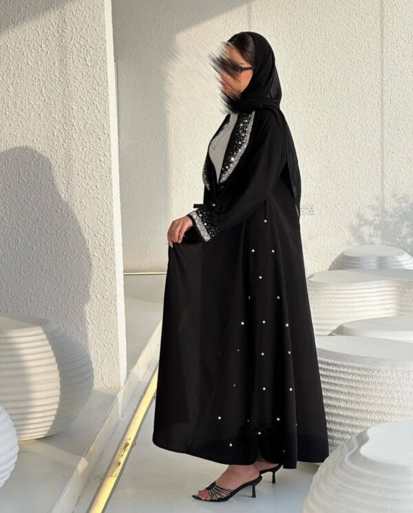 Eine Frau in der Royal Krepp-Abaya zeigt die Seitenansicht, mit eleganten Details an Ärmeln und Saum, kombiniert mit Absätzen.