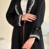 Eine Frau präsentiert die Royal Krepp-Abaya in einer vollständigen Vorderansicht, die das luxuriöse Design und die feinen Details hervorhebt.