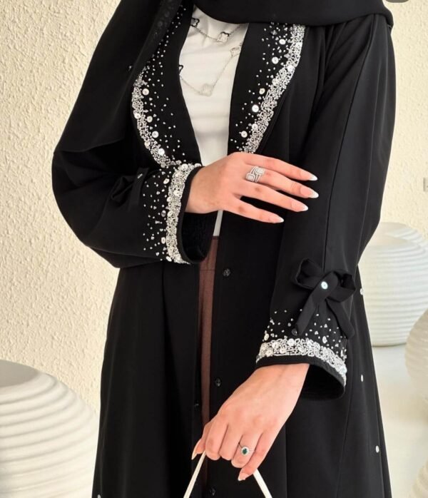 Eine Frau präsentiert die Royal Krepp-Abaya in einer vollständigen Vorderansicht, die das luxuriöse Design und die feinen Details hervorhebt.