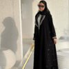 Eine Frau präsentiert die Royal Krepp-Abaya in einer vollständigen Vorderansicht, die das luxuriöse Design und die feinen Details hervorhebt.