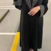 A lady wearing the Royal Samtweiche Abaya 'Essence,' standing elegantly in a parking lot, blending timeless sophistication with an urban backdrop.