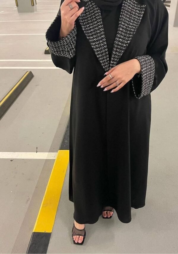 A lady wearing the Royal Samtweiche Abaya 'Essence,' standing elegantly in a parking lot, blending timeless sophistication with an urban backdrop.